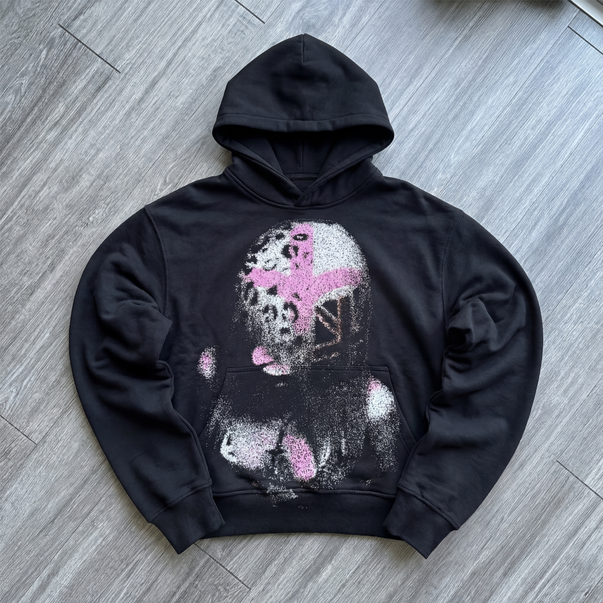 Black hoodie with a graphic design on a gray wooden floor